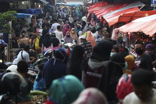 People shop in preparation of the upcoming Eid al-Fitr holiday that marks the end of the holy fasting month of Ramadan amid fears of the new coronavirus outbreak at a market in Jakarta, Indonesia, Friday, May 22, 2020. (Photo by Achmad Ibrahim/AP Photo)