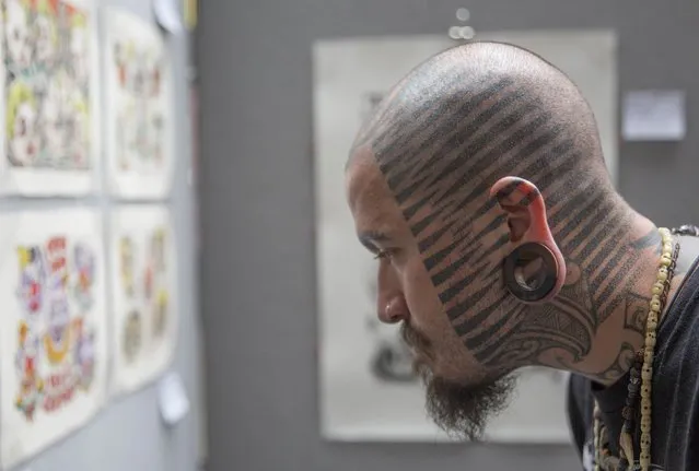 A man browses tattoo designs during the 10th International Tattoo Convention in London September 27, 2014. (Photo by Neil Hall/Reuters)