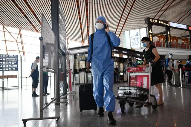 A man wearing a protective suit uses his phone at Beijing's international airport on June 17, 2020. Beijing's airports cancelled more than 1,200 flights and schools in the Chinese capital were closed again on June 17 as authorities rushed to contain a new coronavirus outbreak linked to a wholesale food market. (Photo by AFP Photo/China Stringer Network)