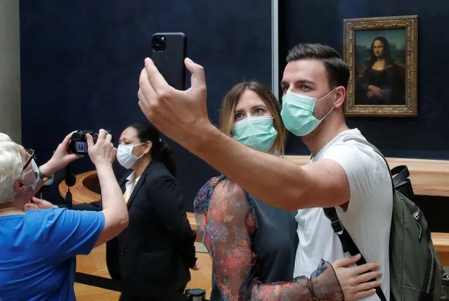 Visitors, wearing protective face masks, make a selfie in front of the “Mona Lisa” (La Joconde) by Leonardo Da Vinci at the Louvre museum in Paris as the museum reopens its doors to the public after almost 4-month closure due to the coronavirus disease (COVID-19) outbreak in France, July 6, 2020. (Photo by Charles Platiau/Reuters)