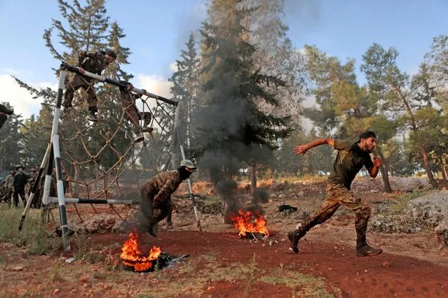 Members of the Hayat Tahrir al-Sham (HTS) jihadist group, which includes leaders of al-Qaeda's former Syria chapter, run after traversing an obstacle as they demonstrate their skills during a graduation for a new batch of fighters in the countryside near Syria's rebel-held northwestern city of Idlib on September 13, 2022. (Photo by Aaref Watad/AFP Photo)