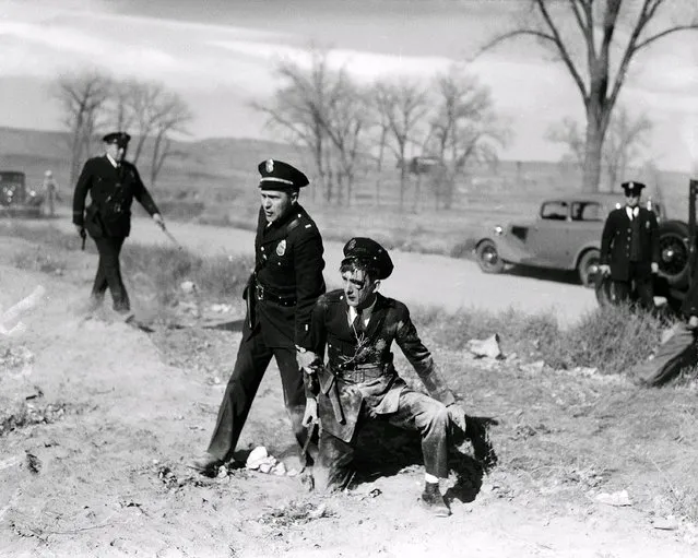 A fellow officer comes to the aid of injured patrolman C.V. Satt, who was pelted with rocks and beer bottles during a clash between police and relief demonstrators in Denver September 23, 1935. (Photo by Henry G. Eisenhand/AP Photo)