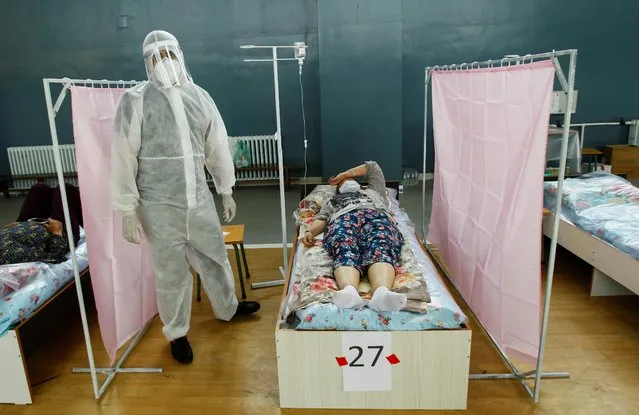 A medical specialist wearing personal protective equipment (PPE) treats patients at a day hospital, which is located in a school gym and provides services free of charge, in Bishkek, Kyrgyzstan on July 16, 2020. The opening of the medical facility amid the coronavirus disease (COVID-19) outbreak was initiated by local businessmen, who currently provide its funding, which includes the purchase of pharmaceuticals, equipment and salaries payment. (Photo by Vladimir Pirogov/Reuters)