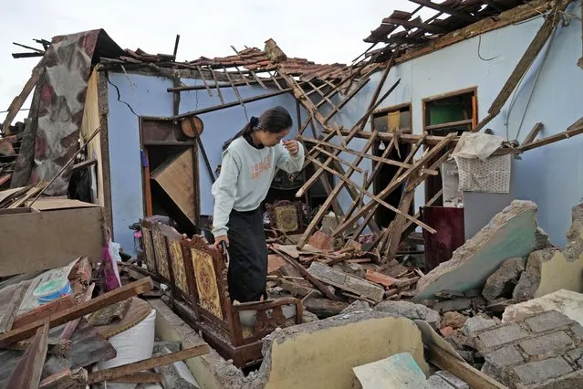 A woman reacts as she inspects her house that was badly damaged during an earthquake in Cianjur, West Java, Indonesia Tuesday, November 22, 2022. The earthquake has toppled buildings on Indonesia's densely populated main island, killing a number of people and injuring hundreds. (Photo by Tatan Syuflana/AP Photo)