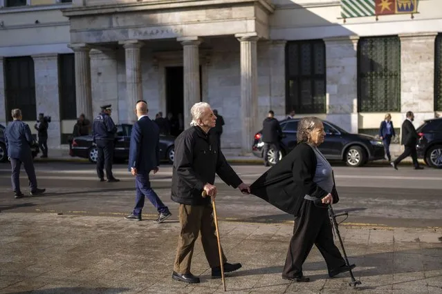 A blind man is helped by a woman as they walk in front of the Athens City Hall, in central Athens , on Thursday , December 1, 2022. (Photo by Petros Giannakouris/AP Photo)