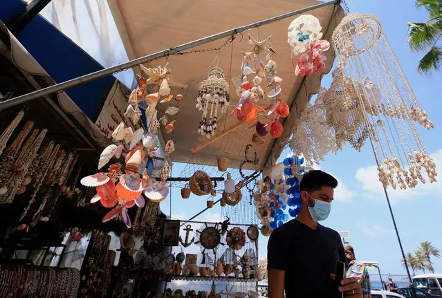 A man wearing a face mask stands in a tourist shop near the closed sea castle of the port city of Sidon, amid concerns over the spread of the coronavirus disease (COVID-19), in Sidon, Lebanon on June 11, 2020. (Photo by Ali Hashisho/Reuters)