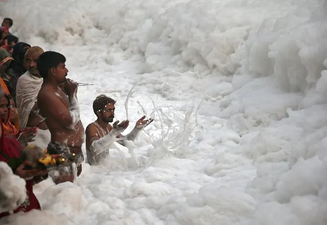 A Hindu devotee pushes the foam away to make space for other devotees to worship the Sun god Surya in the polluted waters of the river Yamuna during the Hindu religious festival of Chatt Puja in New Delhi October 30, 2014. (Photo by Ahmad Masood/Reuters)