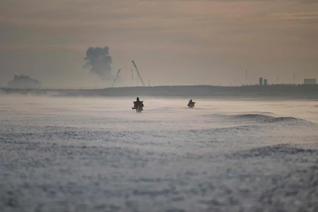 Shrimp fishermen are seen in the waters, with the Gravelines Nuclear Power Station in background, off the beach of Gravelines, near Dunkirk, northern France on October 12, 2022. (Photo by Sameer Al-Doumy/AFP Photo)