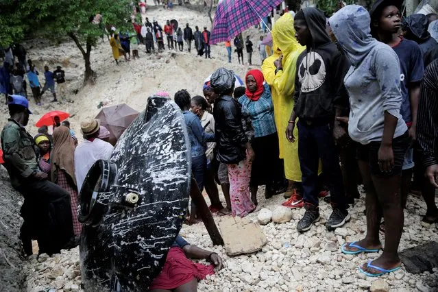 Residents look at the body of a woman who died during the passage of Tropical Storm Laura, in Port-au-Prince, Haiti on August 23, 2020. (Photo by Andres Martinez Casares/Reuters)