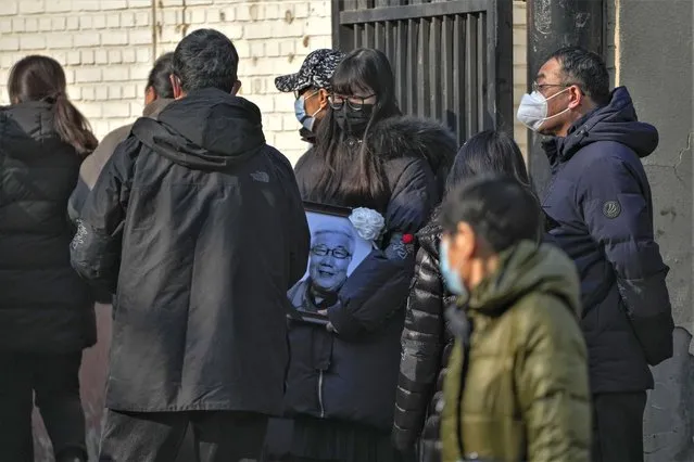 A family member carrying the photo of a deceased relative outside a mortuary of a hospital in Beijing, Thursday, January 5, 2023. (Photo by Andy Wong/AP Photo)