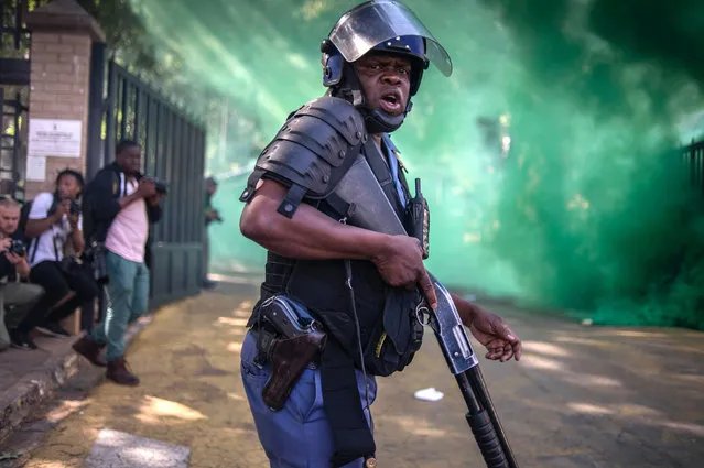 A South African police officer looks on during clashes with students from the University of the Witwatersrand during a protest against university fee increases on September 21, 2016 in Johannesburg, South Africa. South African police fired stun grenades and rubber bullets to disperse protesting students in central Johannesburg, in further outbreaks of unrest over higher tuition fees. (Photo by Mujahid Safodien/AFP Photo)