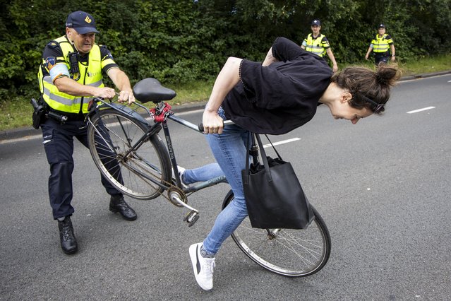 A policeman stops a cyclist as demonstrators from Extinction Rebellion (XR) protest during the NATO Summit by blocking the A12 highway in The Hague, The Netherlands, 25 June 2025. The Netherlands, for the first time in NATO's history of existence, is hosting a NATO summit. (Photo by Sebastiaan Barel/EPA)