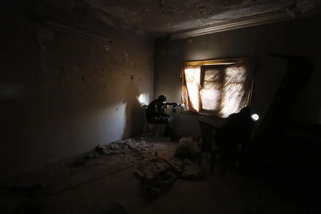 Al-Mujahideen army fighters, which operates under the Free Syrian Army, sit in shooting positions inside a damaged room during clashes with forces loyal to Syria's President Bashar al-Assad on the Zeno street frontline in Aleppo November 18, 2014. (Photo by Hosam Katan/Reuters)