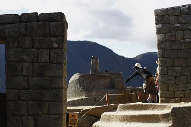 A visitor touches the Intihuatana solar clock, believed to generate “good energy”, at the Inca citadel of Machu Picchu in Cusco December 2, 2014. (Photo by Enrique Castro-Mendivil/Reuters)