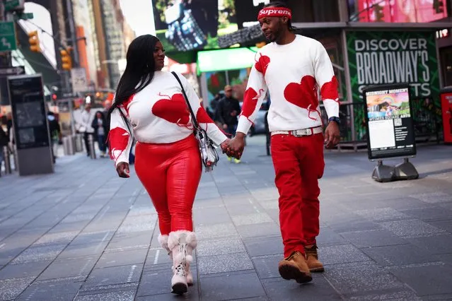 A couple in matching heart themed sweaters walk hand in hand through Times Square on Valentine's Day in New York City, New York, U.S., February 14, 2023. (Photo by Mike Segar/Reuters)