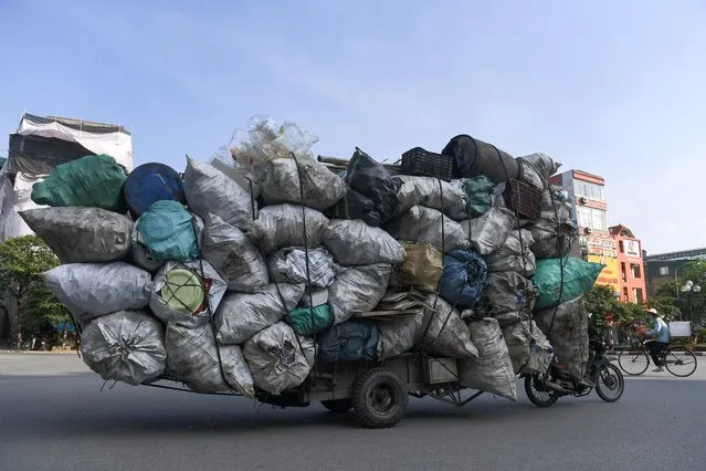 A waste collector on a motorbike transports a large pile of plastic scrap for recycling in Hanoi on October 27, 2020. (Photo by Nhac Nguyen/AFP Photo)