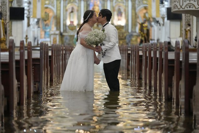 Newlyweds Jade Rick Verdillo right, and Jamaica kiss during their wedding at the flooded Barasoain church in Malolos, Bulacan province, Philippines on Tuesday, July 22, 2025. (Photo by Aaron Favila/AP Photo)