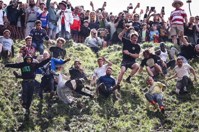 Competitors come tumbling down the hill in pursuit of a round Double Gloucester cheese during the annual Cooper's Hill cheese rolling competition near the village of Brockworth, Gloucester, in western England, on May 27, 2024. The annual Cooper's Hill Cheese Rolling involves competitors chasing an eight pound Double Gloucester cheese down a steep hill. (Photo by Henry Nicholls/AFP Phoot)