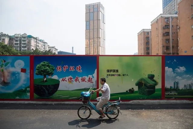 A man cycles past a fenced up construction site in Baishizhou, Shenzhen, Guangdong Province, China, September 27, 2016. Baishizou, home to about 150,000 people, is one of the last “urban villages” of Shenzhen and is scheduled to be torn down to make way for new residential towers, malls and hotels. (Photo by EPA/Stringer)