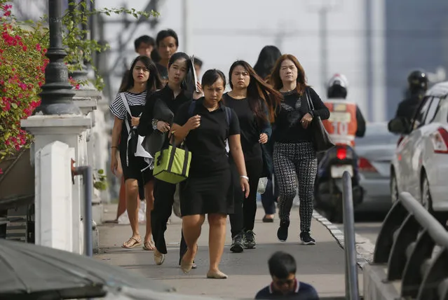 In this October 12, 2017, photo, morning commuters cross a bridge dressed in black in honor of the late King of Thailand in Bangkok, Thailand. The muted colors of mourning have settled over Bangkok once again in recent weeks as the country marks a year since the death of its beloved monarch, King Bhumibol Adulyadej, and prepares for the national spectacle of his cremation next week. (Photo by Wally Santana/AP Photo)