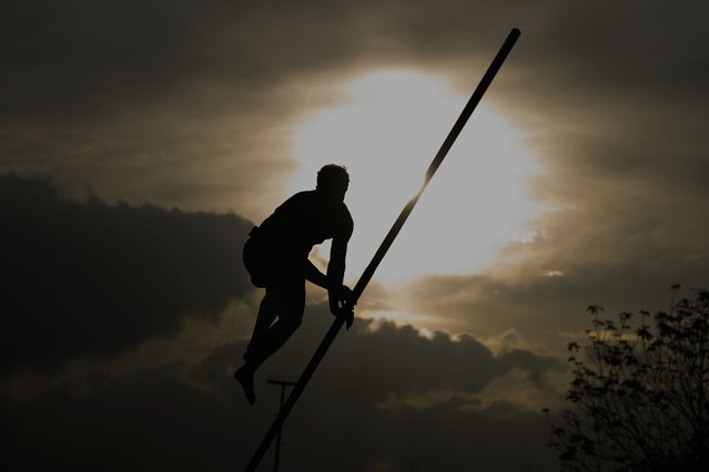 An athlete climbs a long carbon pole while jumping across a body of water during a Fierljeppen competition in Kockengen, Netherlands, Wednesday, August 27, 2025. (Photo by Peter Dejong/AP Photo)