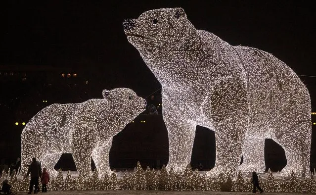 People walk near huge light sculptures of polar bears installed as part of decoration for the New Year and Christmas holidays in a district of Moscow, Russia, 14 December 2020. Moscow's Mayor Sobyanin said that there will be no massive New Year celebrations in the city this year due to the ongoing pandemic of the COVID-19 disease caused by the SARS-CoV-2 coronavirus. (Photo by Sergei Ilnitsky/EPA/EFE)