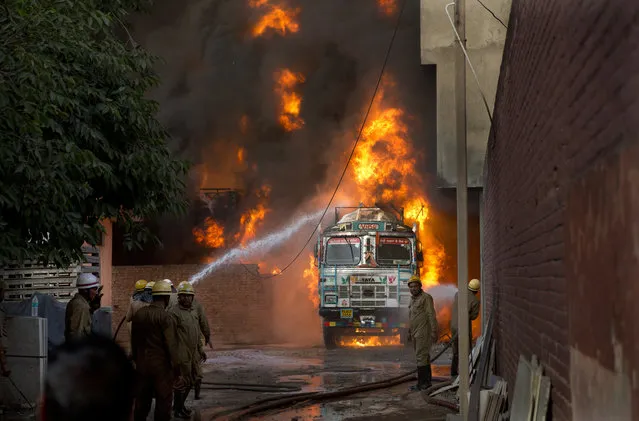Firefighters work to douse flames on a truck in New Delhi, India, Tuesday, May 29, 2018. The fire that started in a truck spread to a nearby warehouse. No casualties have been reported. (Photo by Manish Swarup/AP Photo)