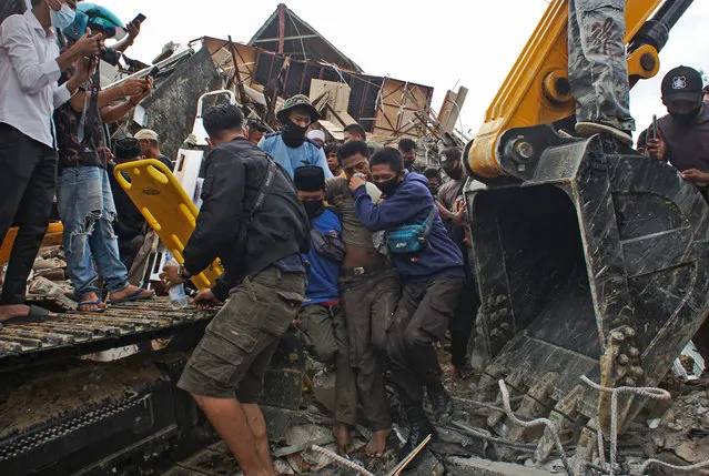Rescuers assist a survivor pulled out from the ruin of a government building collapsed during an earthquake in Mamuju, West Sulawesi, Indonesia, Friday, January 15, 2021. A strong, shallow earthquake shook Indonesia's Sulawesi island just after midnight Friday, toppling homes and buildings, triggering landslides and killing a number of people. (Photo by Azhari Surahman/AP Photo)