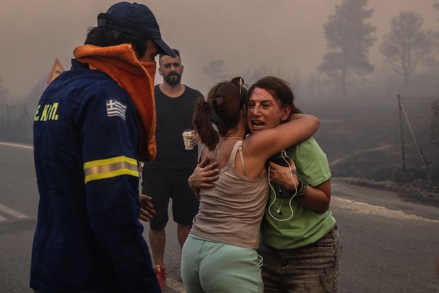 Women embrace after being rescued during a wildfire in Varnavas, north of Athens, on August 11, 2024. (Photo by Angelos Tzortzinis/AFP Photo)