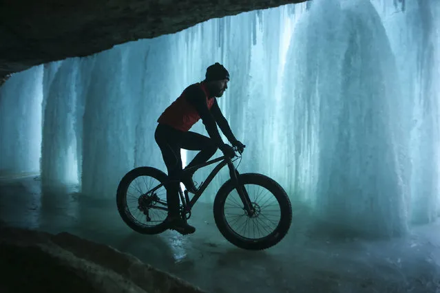 While on his lunch hour, Jesse LaLonde rides a fat tire bike up Minnehaha Creek to get a look at Minnehaha Falls Tuesday, January 13, 2015 in Minneapolis. A steady stream of visitors descended on the falls Tuesday to view the frozen water and perhaps venture behind the falls. (Photo by Jeff Wheeler/AP Photo/The Star Tribune)