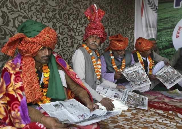 Farmers read local newspapers as they participate in a day-long hunger strike to protest against farm laws at the Delhi-Uttar Pradesh border, on the outskirts of New Delhi, India, Saturday, January 30, 2021. Indian farmers and their leaders spearheading more than two months of protests against new agriculture laws began a daylong hunger strike Saturday, directing their fury toward Prime Minister Narendra Modi and his government. Farmer leaders said the hunger strike, which coincides with the death anniversary of Indian independence leader Mahatma Gandhi, would reaffirm the peaceful nature of the protests. (Photo by Manish Swarup/AP Photo)