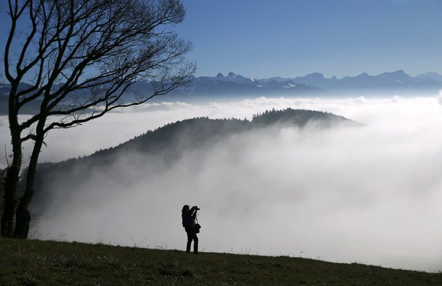 A woman  photographs a sea of fog over Lake Leman at the Tour de Gourze near Lausanne, Switzerland, December 3, 2015. (Photo by Denis Balibouse/Reuters)