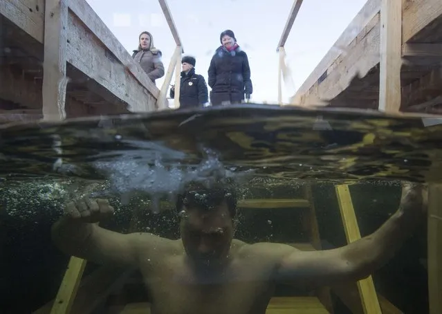 A man immerses himself in an ice hole in the Moskva river during celebrations for Russian Orthodox Epiphany on the outskirts of Moscow January 19, 2015. Orthodox believers mark Epiphany on January 19 by immersing themselves in icy waters regardless of the weather. (Photo by Maxim Shemetov/Reuters)