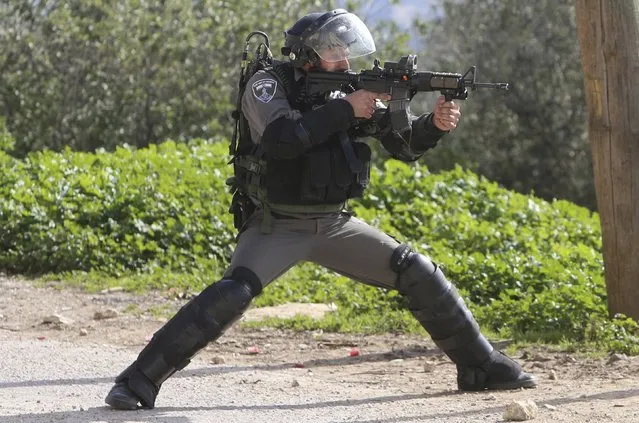 An Israeli border policeman points his weapon at Palestinian protesters during clashes following a protest against the nearby Jewish settlement of Qadomem, in the West Bank village of Kofr Qadom near Nablus January 23, 2015. (Photo by Abed Omar Qusini/Reuters)