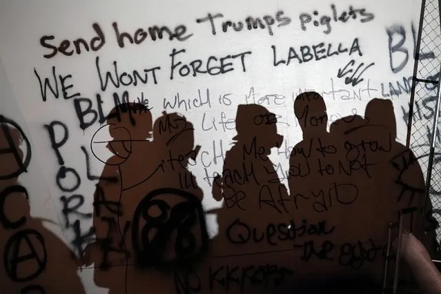 The silhouette of demonstrators is seen against a wall covered in graffiti during a protest against racial inequality in front of the federal courthouse in Portland, Oregon, U.S. July 17, 2020. (Photo by Nathan Howard/Reuters)