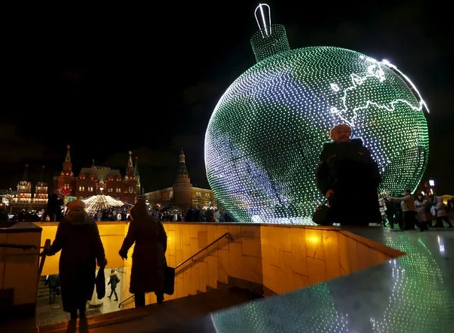 People walk near a giant Christmas ball decorated with festive illumination lights in Manezh square in central Moscow, Russia, December 24, 2015. (Photo by Maxim Zmeyev/Reuters)