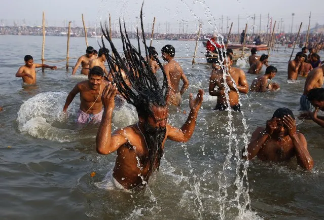 An Indian holy man with other Hindu devotees take holy dips at Sangam, the confluence of the Rivers Ganges, Yamuna and mythical Saraswati on Maghi Purnima, or the full-moon day of the month of Magh during the annual traditional fair of “Magh Mela” in Allahabad, India, Tuesday, February 3, 2015. (Photo by Rajesh Kumar Singh/AP Photo)