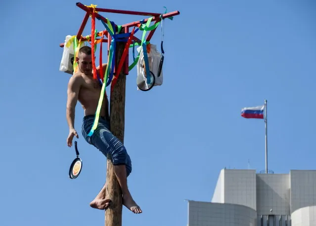 A man drops a skillet, which he gets as a prize after climbed up a wooden pole, during celebrations of Maslenitsa, also known as Pancake Week, which is a pagan holiday marking the end of winter, in Russia's far eastern city of Vladivostok, Russia on March 14, 2021. (Photo by Yuri Maltsev/Reuters)