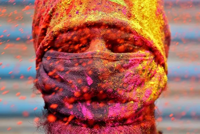 A man wearing a protective face mask reacts as colour powder is thrown towards him during Holi celebrations, amidst the spread of the coronavirus disease (COVID-19), in Chennai, India, March 29, 2021. (Photo by P. Ravikumar/Reuters)
