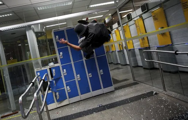 A demonstrator attacks a Brasil bank branch during a protest against fare hikes for city buses in Sao Paulo, Brazil, January 8, 2016. (Photo by Nacho Doce/Reuters)