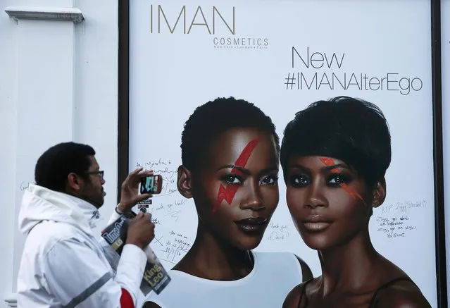 A man photographs an Iman cosmetics advert signed with messages of condolence following the death of David Bowie, in Brixton, south London, Britain January 12, 2016. Sales of David Bowie's last album - released two days before his death from cancer - have soared along with downloads of his greatest hits, testimony to the powerful appeal of a pioneer in pop culture and the music business. (Photo by Stefan Wermuth/Reuters)