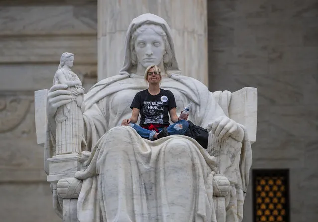 Jessica Campbell-Swanson, an activist from Denver, sits in the lap of a sculpture known as the Statue of Contemplation of Justice on the steps of the Supreme Court Building where she and others protested the confirmation of Brett Kavanaugh as the high court's newest justice, in Washington, Saturday, October 6, 2018. Kavanaugh took the oath inside the building after the bitterly polarized U.S. Senate narrowly confirmed him, delivering an election-season triumph to President Donald Trump that could swing the court rightward for a generation. (Photo by J. Scott Applewhite/AP Photo)