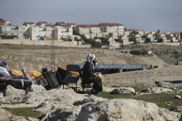 A Palestinian man smokes a cigarette as he sits near his belongings after the Israeli army demolished his shanty, that his family lives in, near the Israeli West Bank settlement of Maale Adumim, near Jerusalem January 6, 2016. The owners of the shanty said they were informed by the Israeli army that the demolition was carried out because they did not have Israeli-issued permits to reside in the area. (Photo by Mohamad Torokman/Reuters)