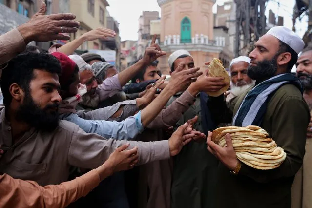 People receive free bread during the fasting month of Ramadan, amid the coronavirus pandemic in Peshawar, Pakistan, 20 April 2021. Muslims around the world celebrate the holy month of Ramadan by praying during the night time and abstaining from eating, drinking, and sexual acts during the period between sunrise and sunset. Ramadan is the ninth month in the Islamic calendar and it is believed that the revelation of the first verse in Koran was during its last 10 nights. (Photo by Arshad Arbab/EPA/EFE)