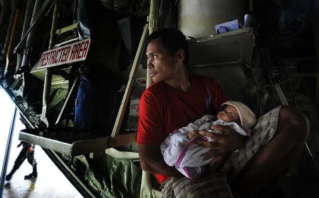 Manuel Aballe holds his 2-month-old daughter Richelyn inside a government plane waiting to leave Tacloban. (Photo by Jes Aznar/The New York Times)