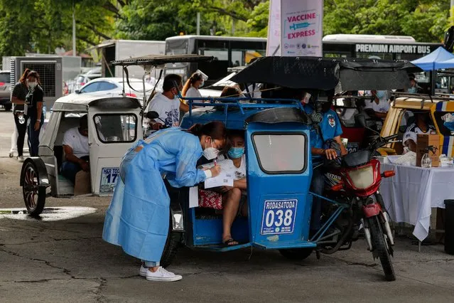 People inside tricycles are interviewed by health workers before their COVID-19 vaccination at a parking lot in Manila, Philippines, 22 June 2021. Philippines' President Rodrigo Duterte threatened to jail people who refuse to be vaccinated following reports of low turnouts in various vaccinate sites. (Photo by Mark R. Cristino/EPA/EFE)