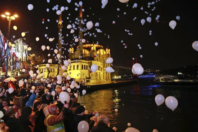 People release balloons and lanterns in the air in Istanbul's Ortakoy district by the Bosphorus, during New Year's cerebrations early Sunday, January 1, 2017. (Photo by Emrah Gurel/AP Photo)