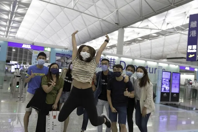 A girl jumps as she poses for a picture with her family before departing to the UK in Hong Kong, China on July 17, 2021. As the deadline of “Leave outside the Rules” (LOTR) for BN(O) visa expires on July 21, there is a special allowance for HongKongers to apply for visa after landing in UK. The last two days, HongKongers rushed to leave their beloved city to immigrate to UK in different mood, Excited for future or hugging each other and weeps. Thousands of Hong Kongers are expected to leave for the UK and other democracies, as the city has been facing intensifying crackdown on human rights and freedom following Chinas National Security Law, with impacts on its economy amid the COVID-19 pandemic. (Photo by Alex Chan Tsz Yuk/SOPA Images/LightRocket via Getty Images)