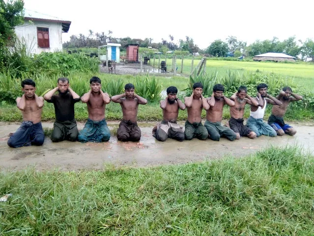 Ten Rohingya Muslim men with their hands bound kneel in Inn Din village, Myanmar. The image, by an unknown photographer, was one of three provided to Reuters by a Buddhist village elder taken during the September 2017 massacre at Inn Din. The final photograph shows the men's bloodied bodies piled in a shallow grave. (Photo by Reuters/Stringer)