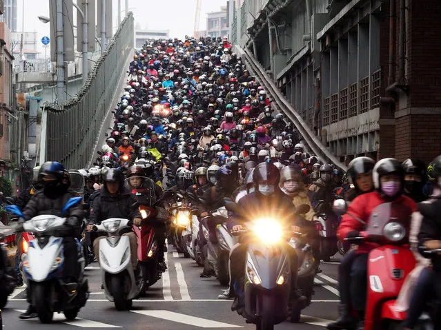 People ride motorcycles across the Taipei Bridge from Sanchung to go to work in Taipei, Taiwan, 01 February 2019. The mass of motorbikes moving down the Taipei Bridge has earned the nickname 'Motorbike Waterfall', attracting many tourists and photographers every morning. Motorbikes are the most common means of transportation in Taiwan, also a main source of air and noise pollution. (Photo by David Chang/EPA/EFE)